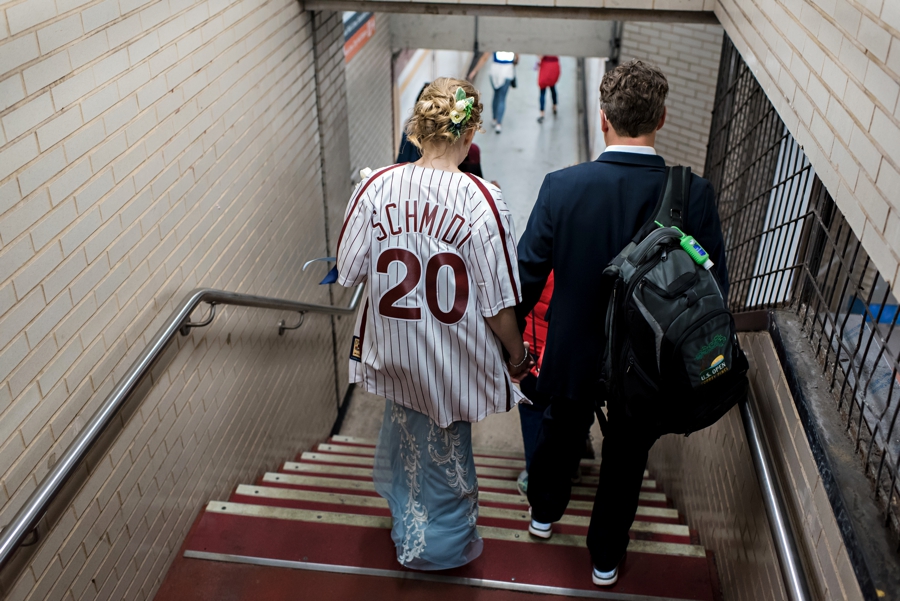 A bride and groom hold hands and walk down the stairs to the subway in Philadelphia.